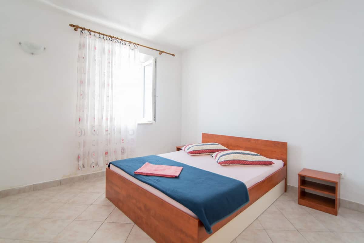 A bedroom with a wooden bed, a blue bedspread, and a small wooden nightstand.