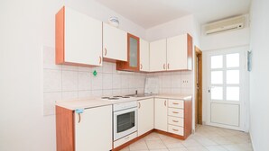 Eine Küche mit weißen Schränken, einem eingebauten Backofen und einem Fenster.