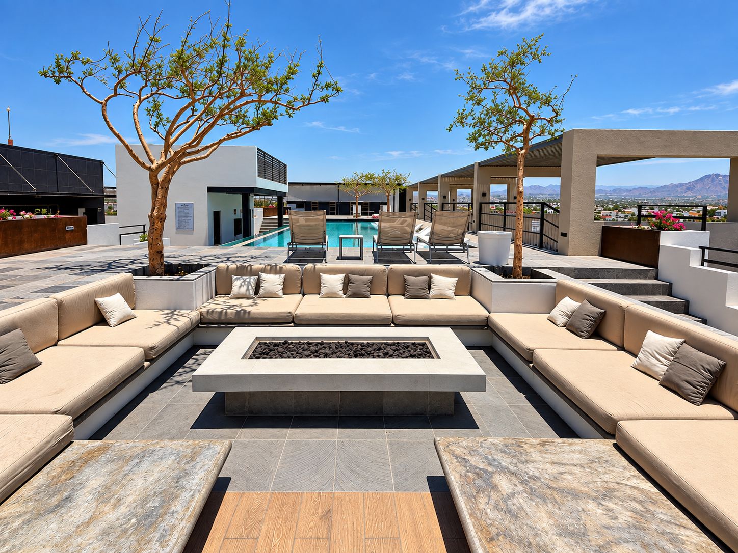 Un área de descanso exterior moderna con piscina, mobiliario y vistas al paisaje.