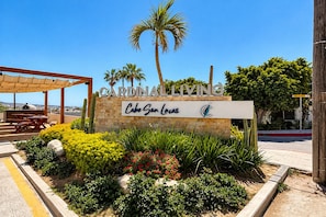 A sign for Cardinal Living in Cabo San Lucas with a patio area and landscaping.