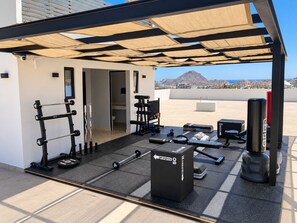 A rooftop gym with exercise equipment, a punching bag, and a view of a mountain and cityscape.