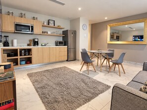 A modern kitchen with wooden cabinets, a built-in microwave, and a refrigerator. There is a dining area with a round table and four chairs.