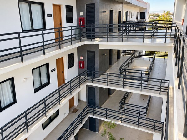 A multi-level building with balconies, staircases, and a view of the sea.
