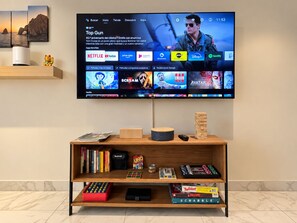 A flat-screen TV mounted on a wall displaying a streaming service interface with various apps and a game console.