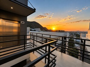 A modern building with a balcony overlooking a cityscape during sunset.