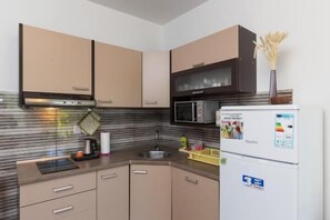 Una cucina compatta con forno a microonde, frigorifero e lavello.