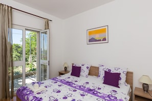 Una camera da letto con un letto, un comodino, una lampada, una finestra con tende e un quadro appeso al muro.