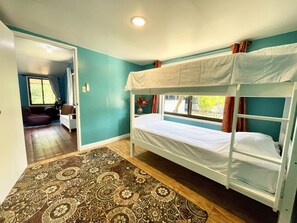 A room with bunk beds, a patterned rug, and a window with curtains. - Cozy 2-bedroom House in Ngermid, Koror (Koror)