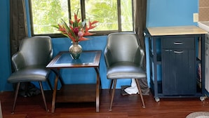 A room with two chairs, a small table, and a cabinet. A window with curtains is visible, and the room has wooden flooring. - Cozy 2-bedroom House in Ngermid, Koror (Koror)