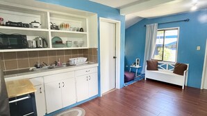 A modern kitchen with white cabinets and a dining area with a wooden table and chairs. - Cozy 2-bedroom House in Ngermid, Koror (Koror)