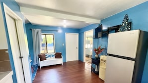 A compact kitchen with a refrigerator, a water dispenser, and a window with a view. - Cozy 2-bedroom House in Ngermid, Koror (Koror)