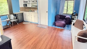 A compact living space with a kitchenette, a dining area, and a seating area with a sofa and ottoman. - Cozy 2-bedroom House in Ngermid, Koror (Koror)