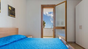 A bedroom with a blue patterned bedspread, a wooden headboard, a nightstand, and a wardrobe. - 2728 Villetta Chiara Blu Primo Piano by Barbarhouse (Melendugno)