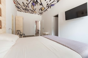 A modern hotel room with a large bed, a flat-screen TV mounted on the wall, and a unique ceiling design. - 2488 Villa Gaia by Perle di Puglia (Cavallino)