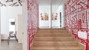 A modern interior with a staircase, wooden flooring, and red abstract wall art. - 2488 Villa Gaia by Perle di Puglia (Cavallino)