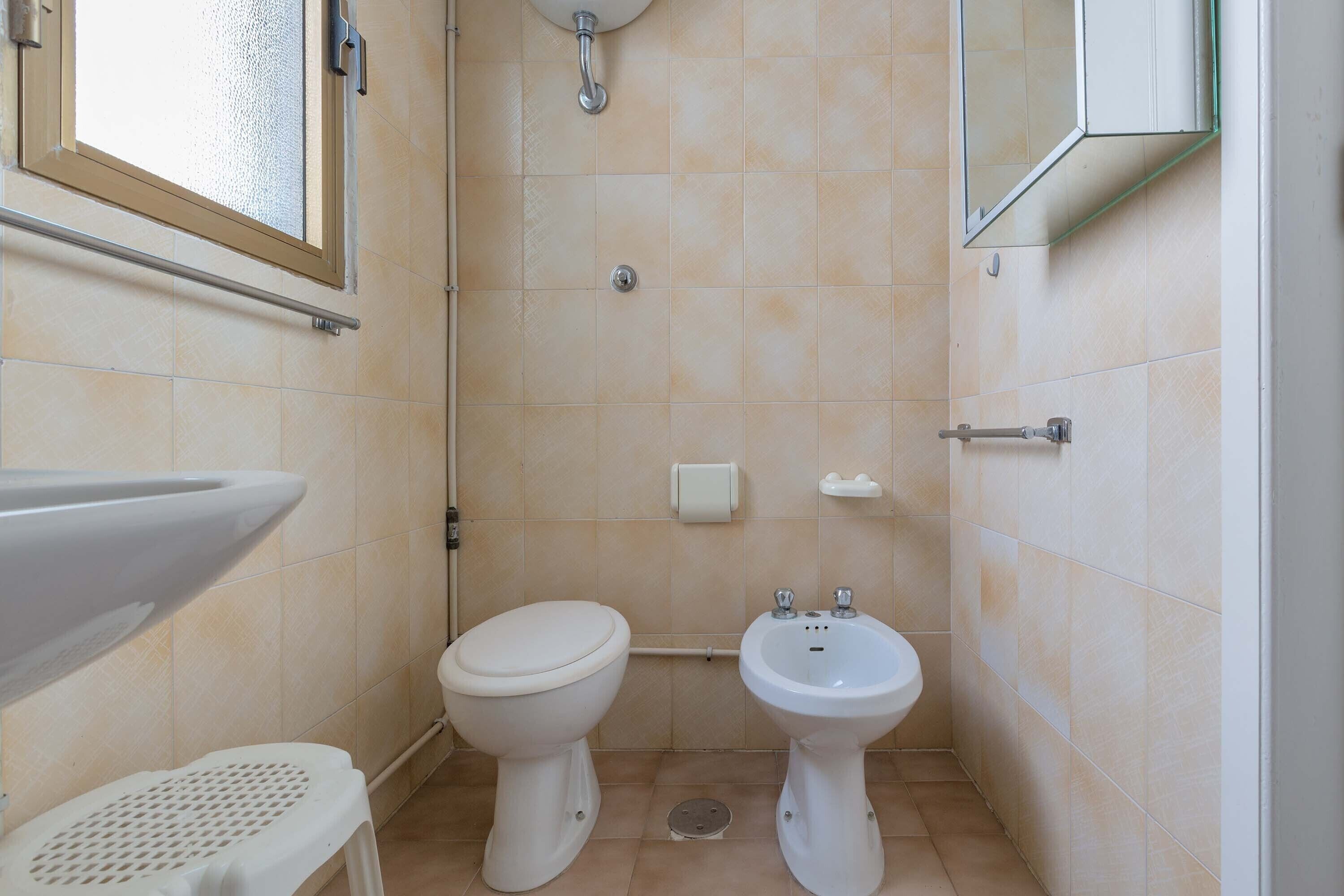A small bathroom with a toilet, bidet, and sink.