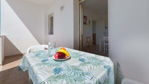 A balcony with a table covered by a leaf-patterned tablecloth, a glass of water, and a bowl of fruit. - 2977 Villetta Idume by Barbarhouse (Lecce)