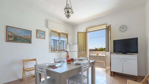 A dining area with a table set for two, a television, and a balcony with a view. - 2977 Villetta Idume by Barbarhouse (Lecce)