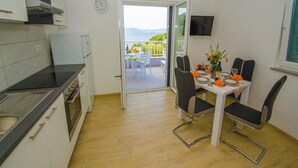 Cozinha moderna com área de refeições, vista para o mar e televisão na parede.