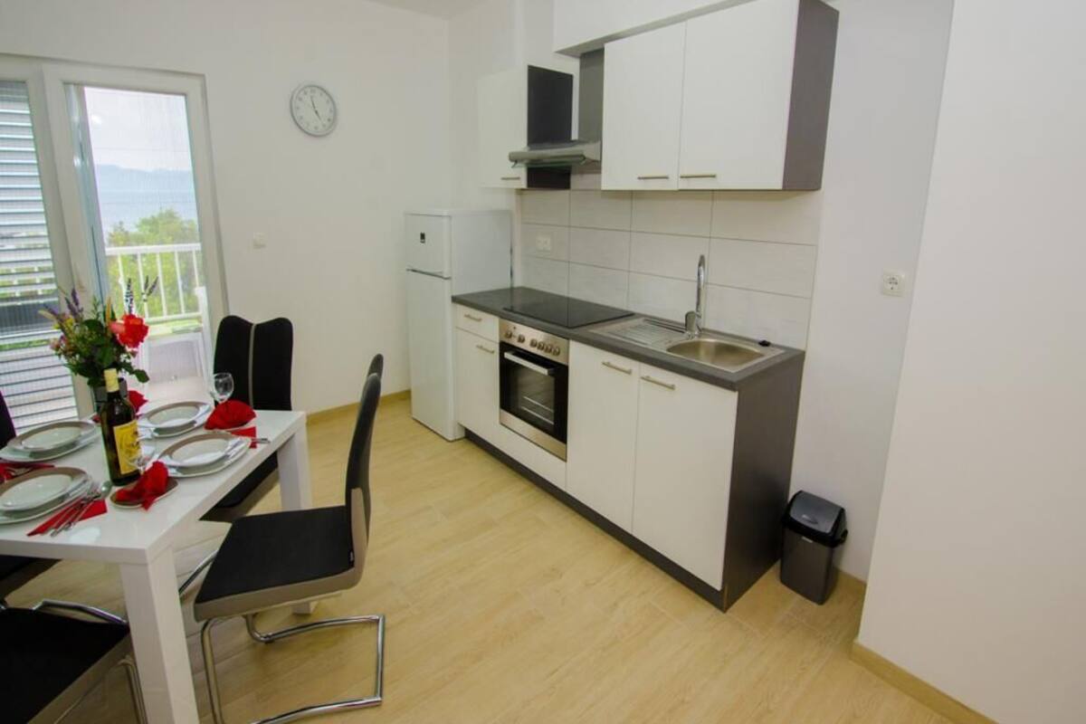 A modern kitchen with white cabinets, a stainless steel oven, and a black countertop.