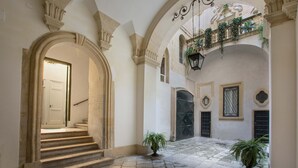 A courtyard with stone steps leading to a white door, surrounded by arches and potted plants. - 2661 Porta del Duomo Luxury by Barbarhouse (Lecce)