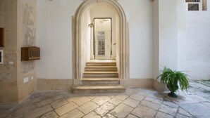 A stone staircase leading to a door with a glass panel, surrounded by a stone floor and a potted plant. - 2661 Porta del Duomo Luxury by Barbarhouse (Lecce)