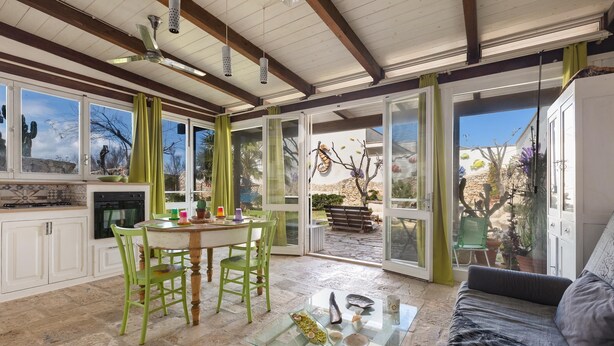 A spacious kitchen with a dining area, a glass coffee table, and a sofa.