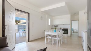 A modern kitchen with white cabinets and a dining area with a white table and chairs. - 3096 Residence Marelena- Villino Tramontana by Barbarhouse (Squinzano)