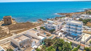 A coastal town with modern buildings, a historic tower, and a clear view of the sea. - 3096 Residence Marelena- Villino Tramontana by Barbarhouse (Squinzano)