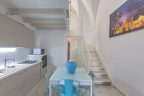 Modern kitchen with central island, dining area, and staircase leading to an upper level.