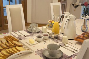 Mesa de café da manhã posta com pão, manteiga, café e suco.