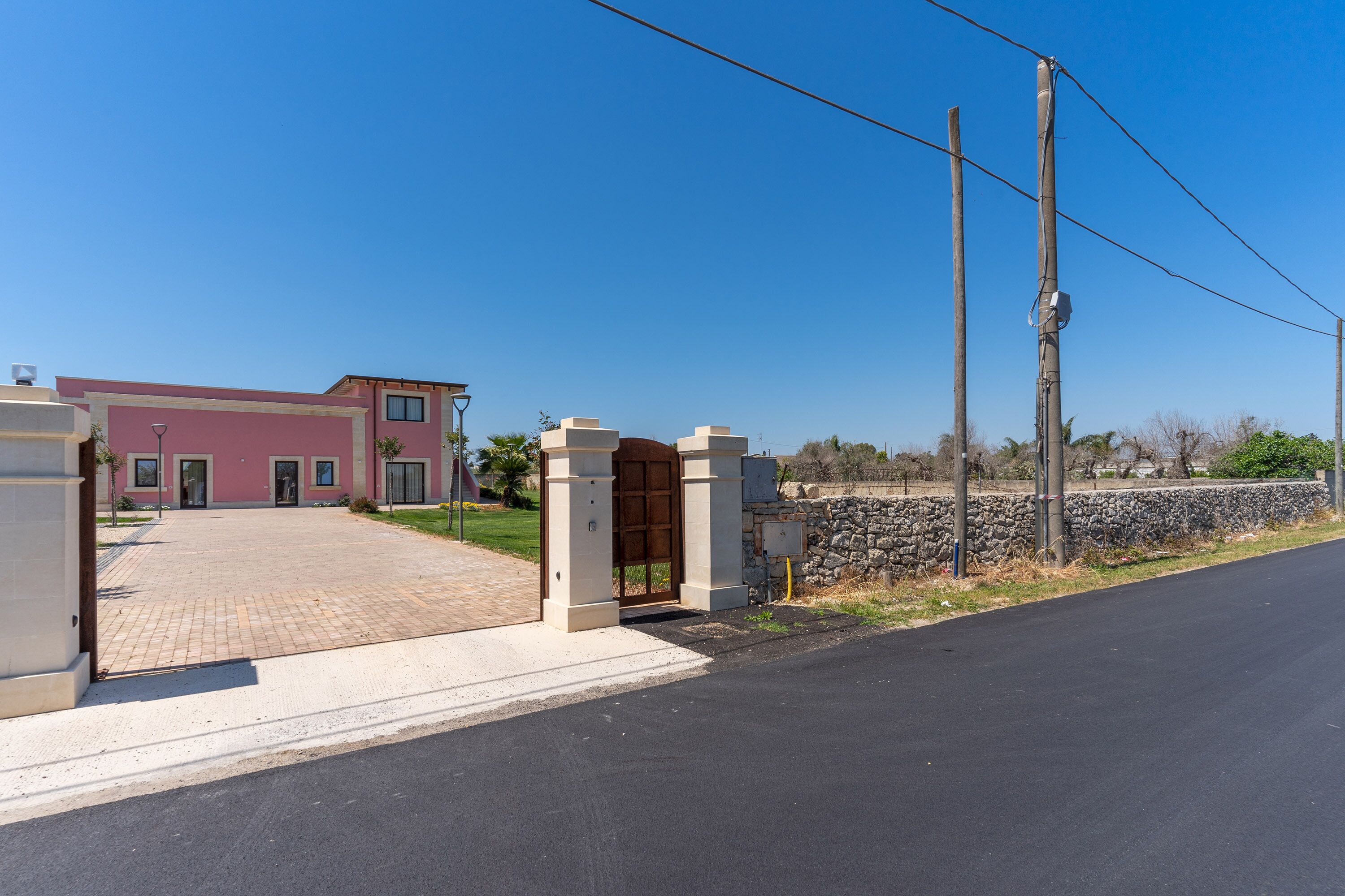 Un bâtiment avec une entrée pavée, un mur en pierre et un ciel dégagé.