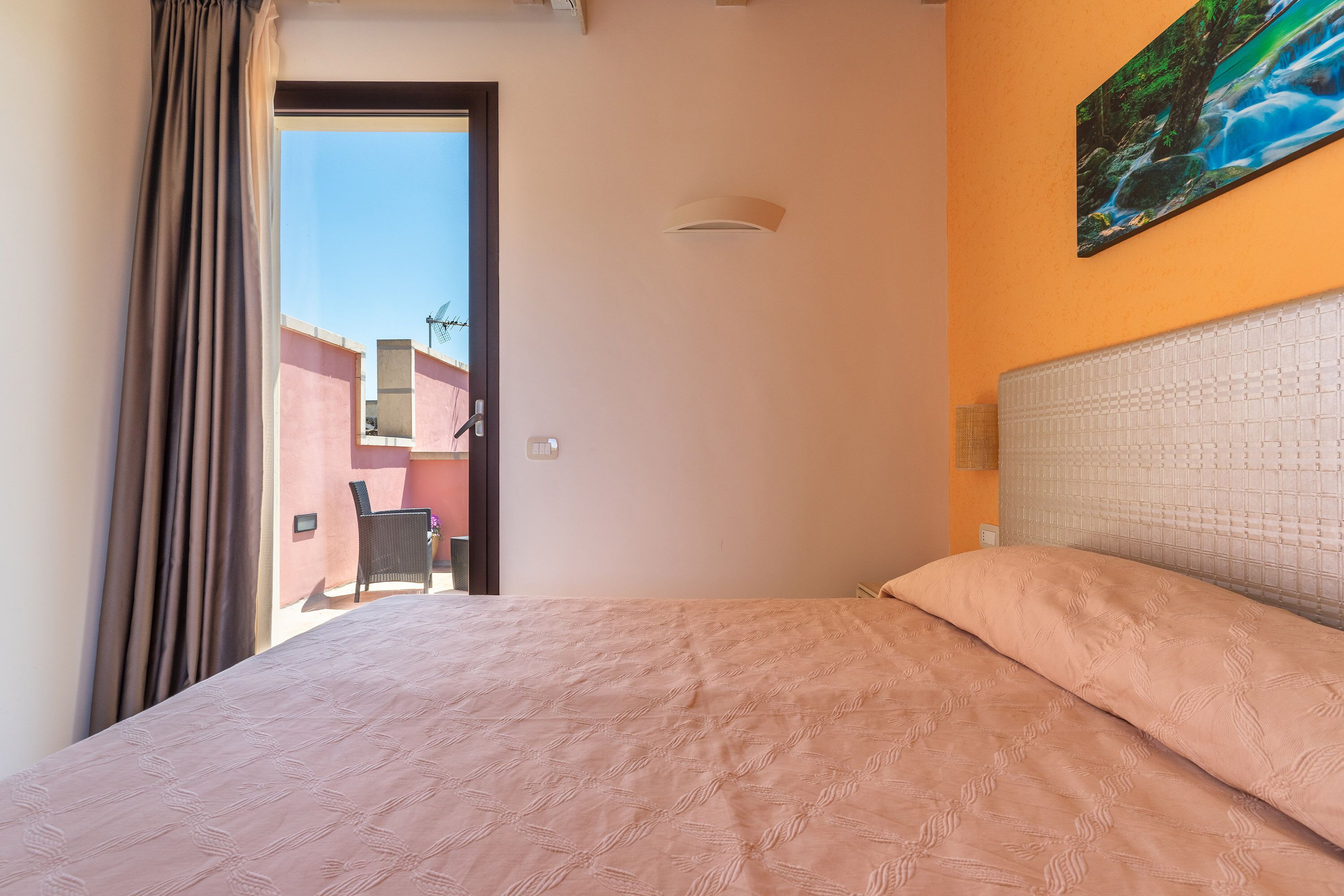 Quarto com cama, um quadro na parede e vista para o exterior.