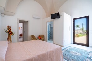 A bedroom with a bed, a TV mounted on the wall, a door leading to a balcony, and a view of the outside. - 2962 Villa di Aurora by Perle di Puglia (San Cesario di Lecce)