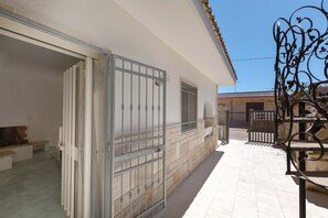 Un edificio con un patio empedrado, una reja de metal y una banca.