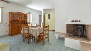 Ein Essbereich mit einem für zwei Personen gedeckten Tisch, Holzstühlen, einem Schrank mit Glastüren und einem Kamin mit Sims.