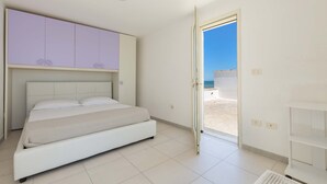 Ein Schlafzimmer mit Bett, Kleiderschrank und einer Tür, die auf einen Balkon führt.