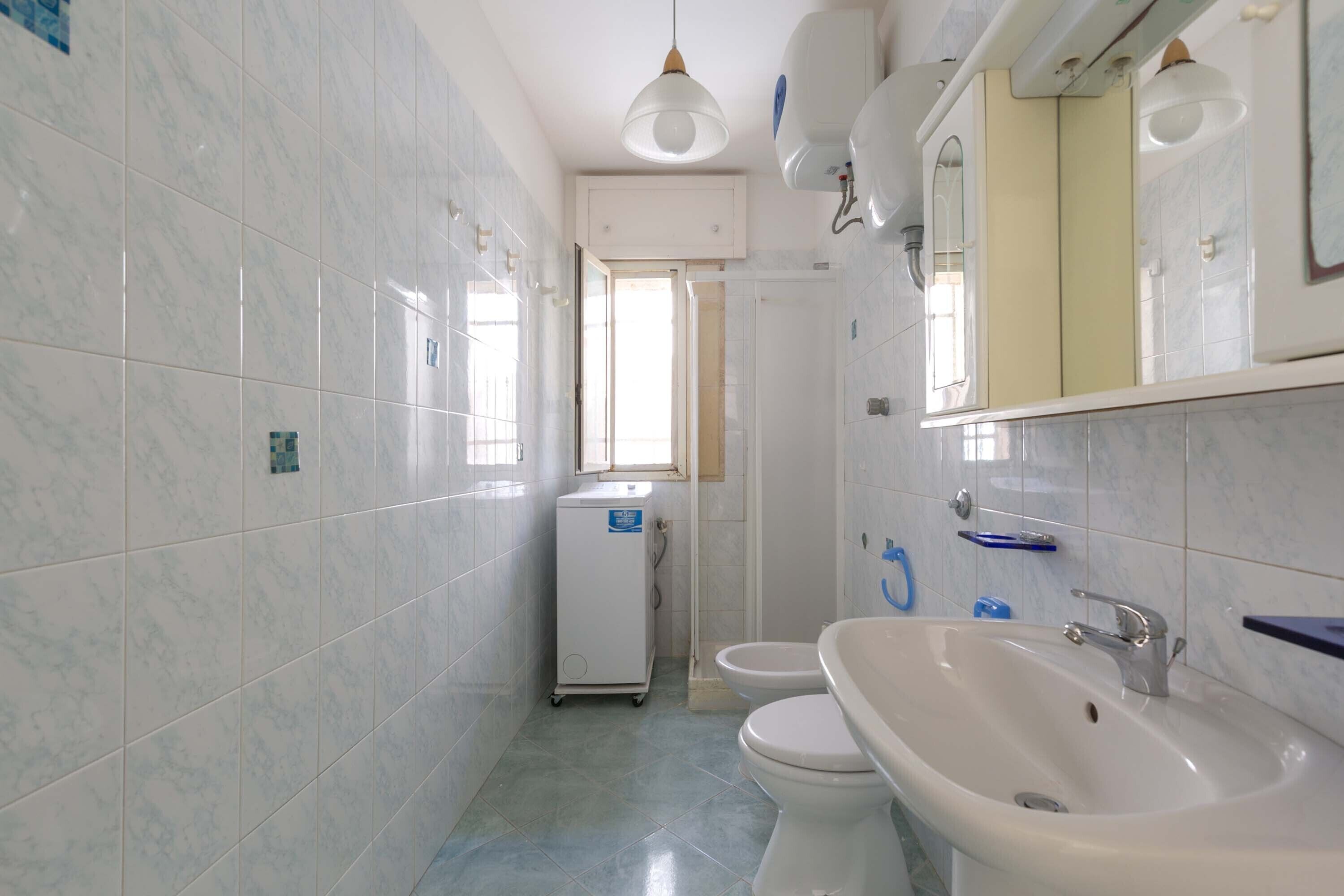 Une salle de bain carrelée de marbre blanc, avec un lavabo, des toilettes et un petit réfrigérateur.
