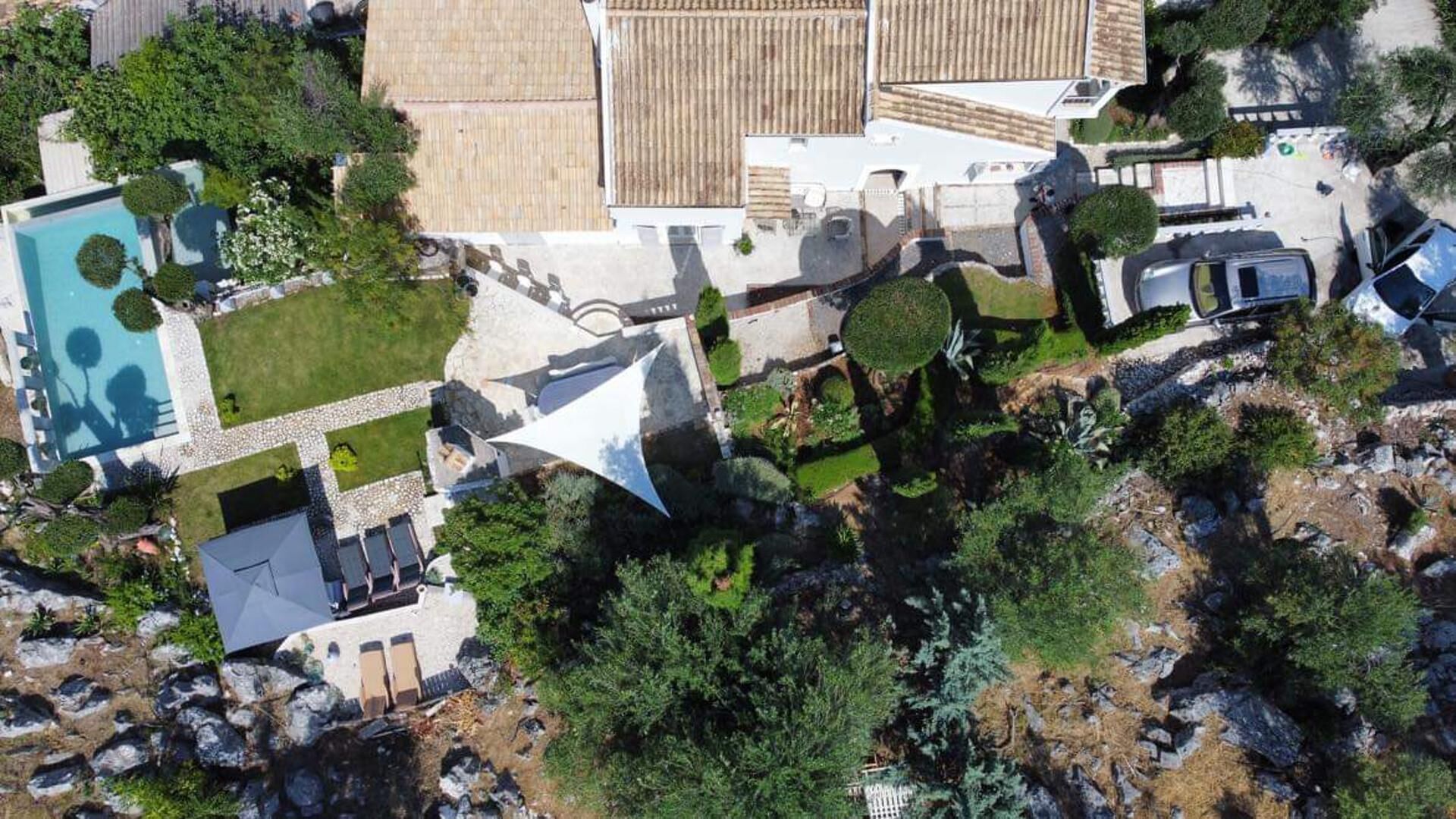 Vista aérea de un complejo turístico con piscina, varias construcciones y zonas ajardinadas.