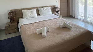 Un dormitorio amplio con una cama grande, una mesita de noche, una lámpara y una ventana con cortinas.