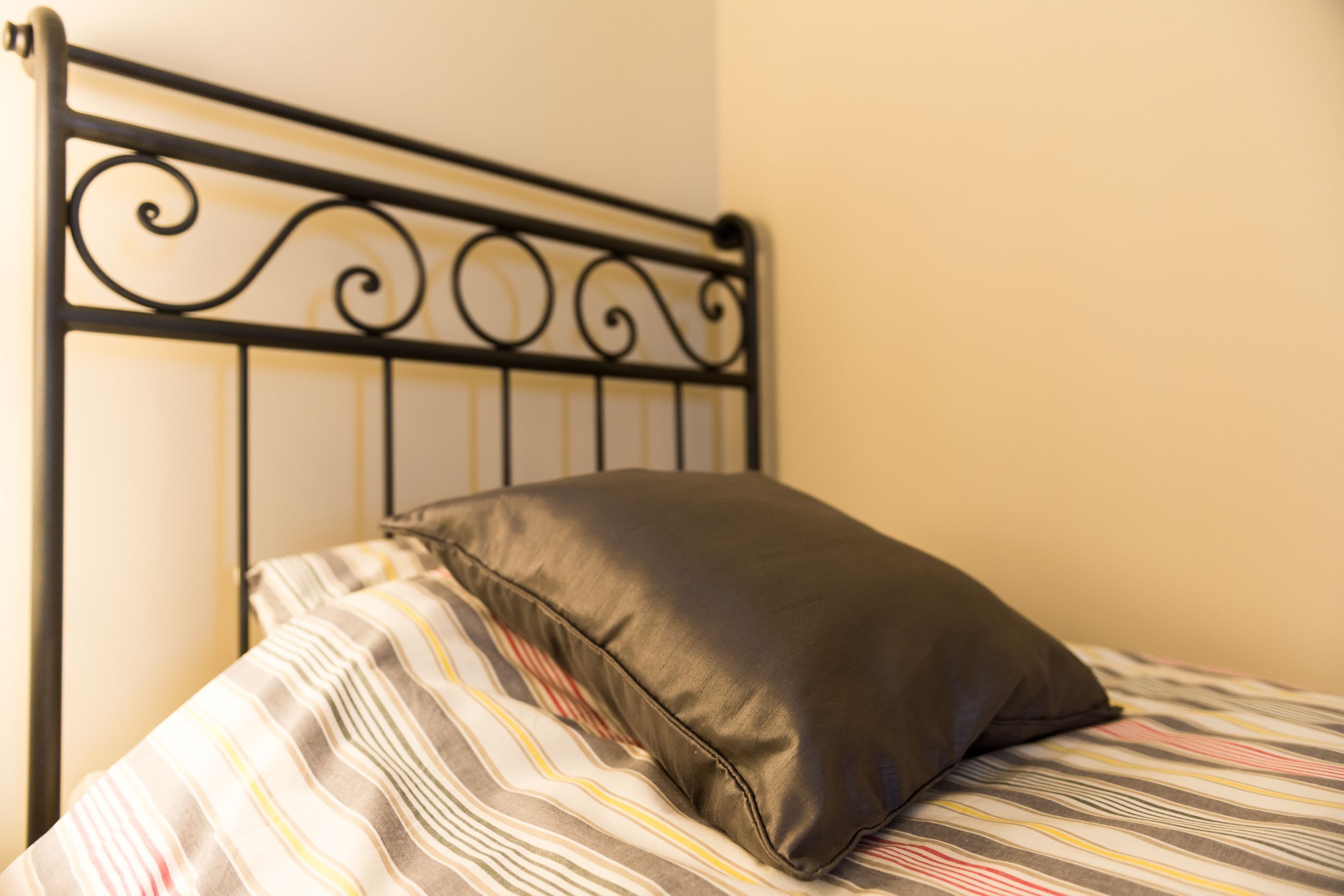 A bed with a metal headboard and a striped bedspread.