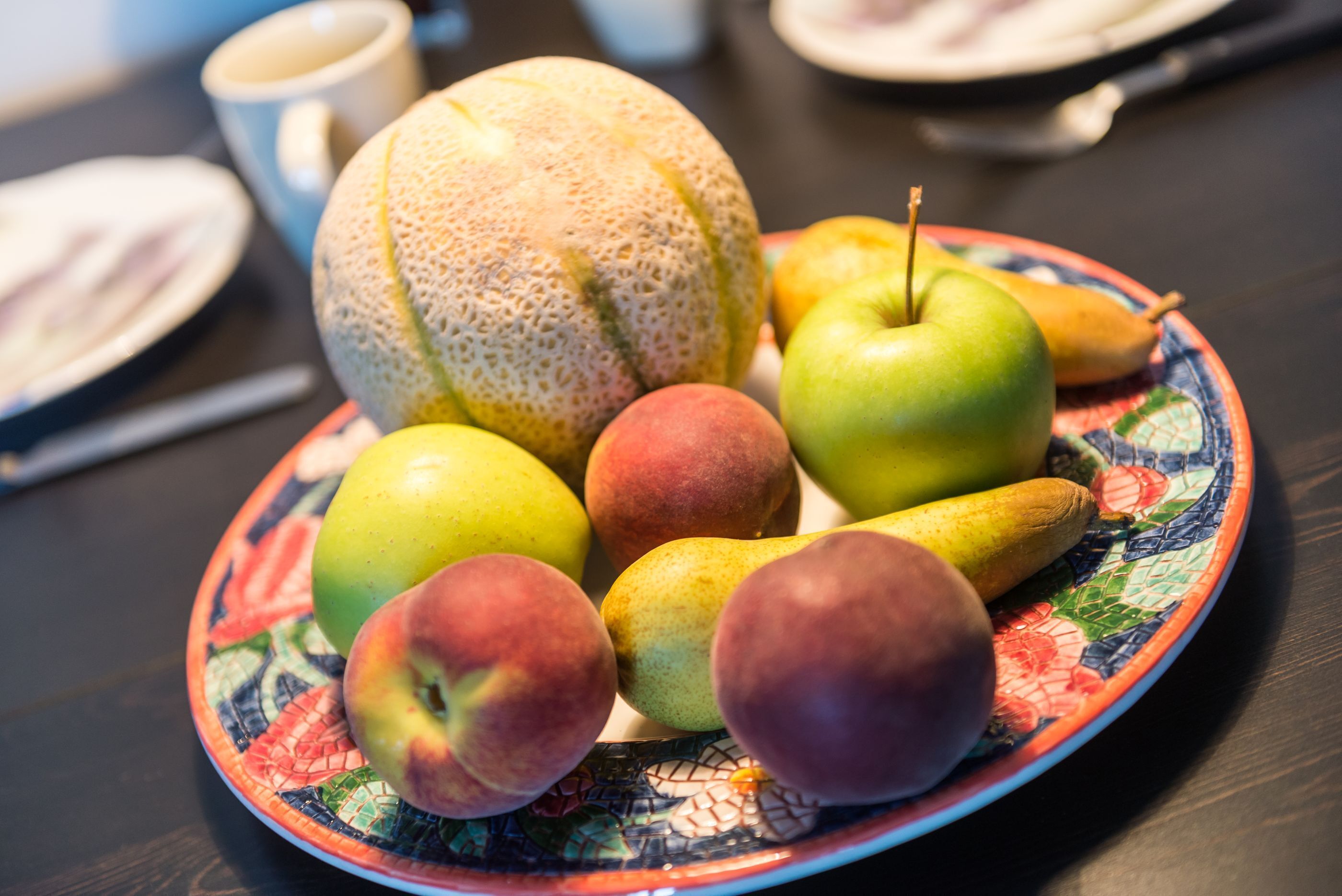 A plate with various fruits including apples, pears, and a melon.