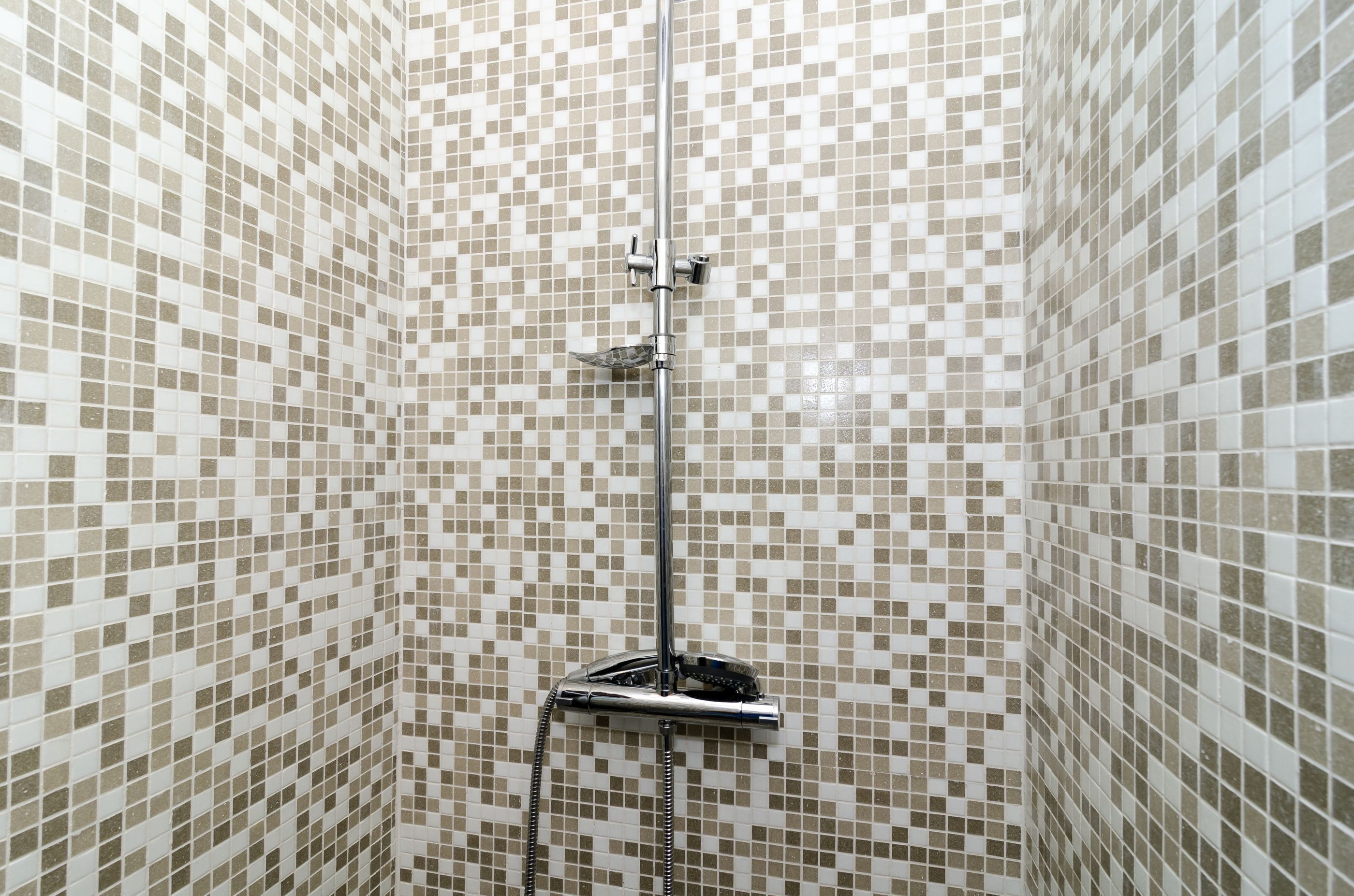 Una ducha con pared de azulejos y cabezal de ducha cromado.