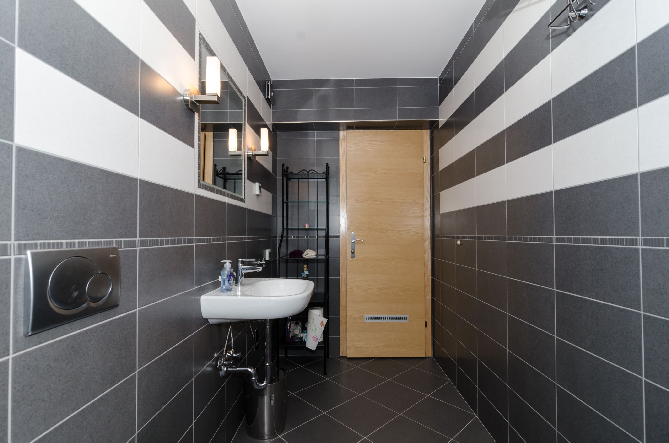 Un bagno moderno con lavandino bianco, specchio e zona doccia.
