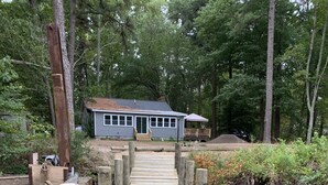 A wooden dock leading to a house with a blue exterior and a covered porch. - Restful River House-private dock- on a golf course-5 mins to downtown Kilmarnock (Kilmarnock)