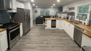 A modern kitchen with stainless steel appliances, a wooden countertop, and a central island. - Restful River House-private dock- on a golf course-5 mins to downtown Kilmarnock (Kilmarnock)