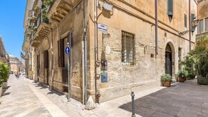 A historic building with a stone facade, a sign indicating a courtyard, and a narrow street with pedestrians. - 3036 Salotto Barocco by Barbarhouse (Lecce)