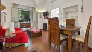 A spacious living area with a red sofa, wooden dining table, and chairs. A television is mounted on the wall, and there is a fireplace in the background. - 3036 Salotto Barocco by Barbarhouse (Lecce)