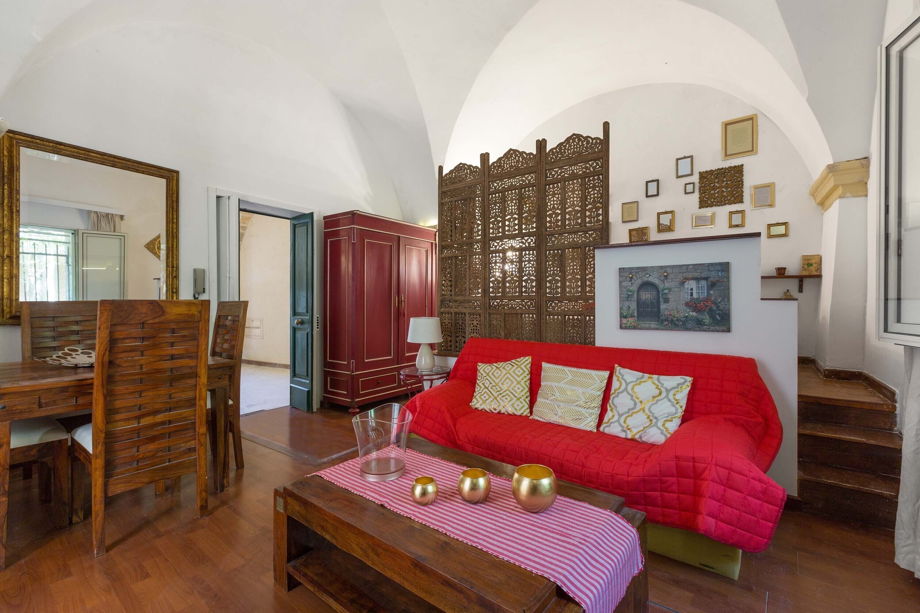 Ein Wohnzimmer mit einem roten Sofa, Holzmöbeln und einem dekorativen Raumteiler.