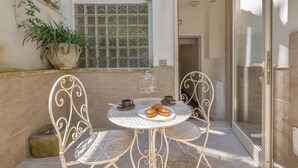 A small outdoor patio with a round table, two chairs, a potted plant, and a glass door leading to a room. - 3036 Salotto Barocco by Barbarhouse (Lecce)